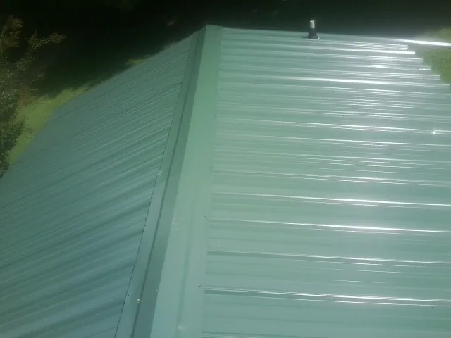 New green metal panels meeting at the ridge of a roof — Flat Roof Repair work by our crew in Cotopaxi