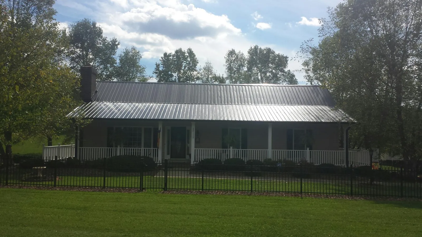 Gray metal roof on a brick ranch with a full width front porch — Gutter Guard Installation work by our crew in Cotopaxi