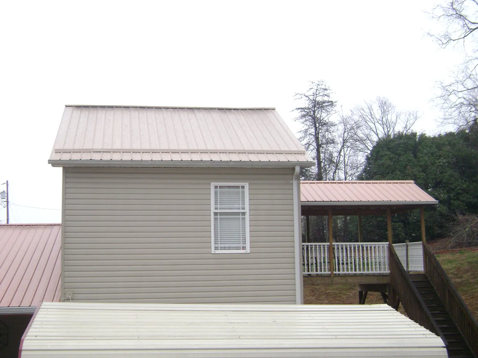 Tan metal roofs on a two story addition and attached porch, from a Roof Replacement job in Cotopaxi
