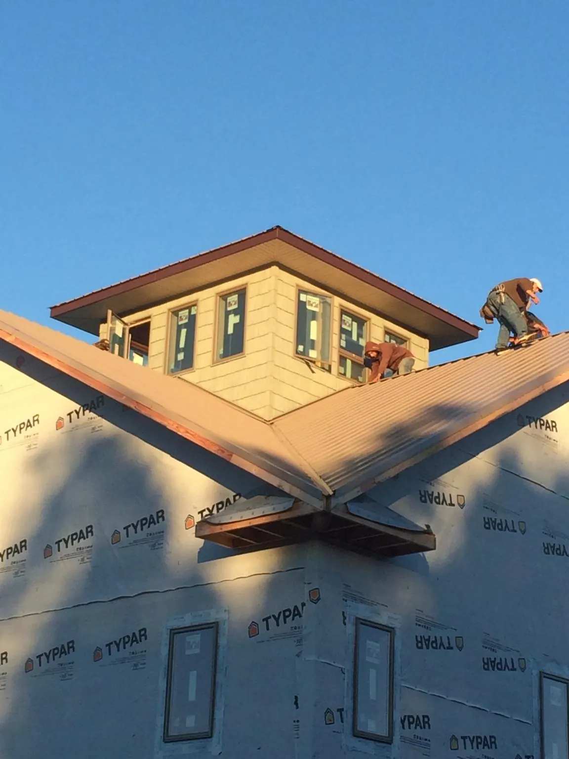 Roofers working around a rooftop cupola on a new metal roof at sunset — Roof Waterproofing in Cotopaxi by Roofing Brothers